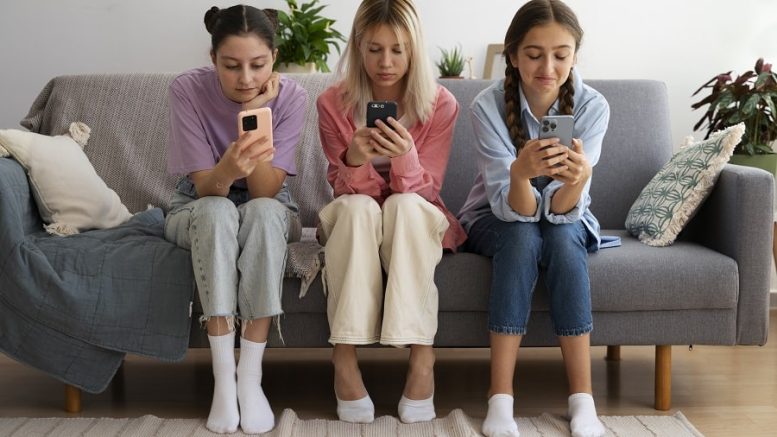 ragazze sedute sul divano con lo smartphone dipendenza
